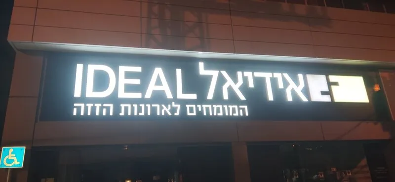 Белые объёмные буквы с подсветкой на тёмном фасаде