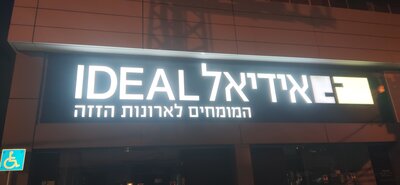 Белые объёмные буквы с подсветкой на тёмном фасаде